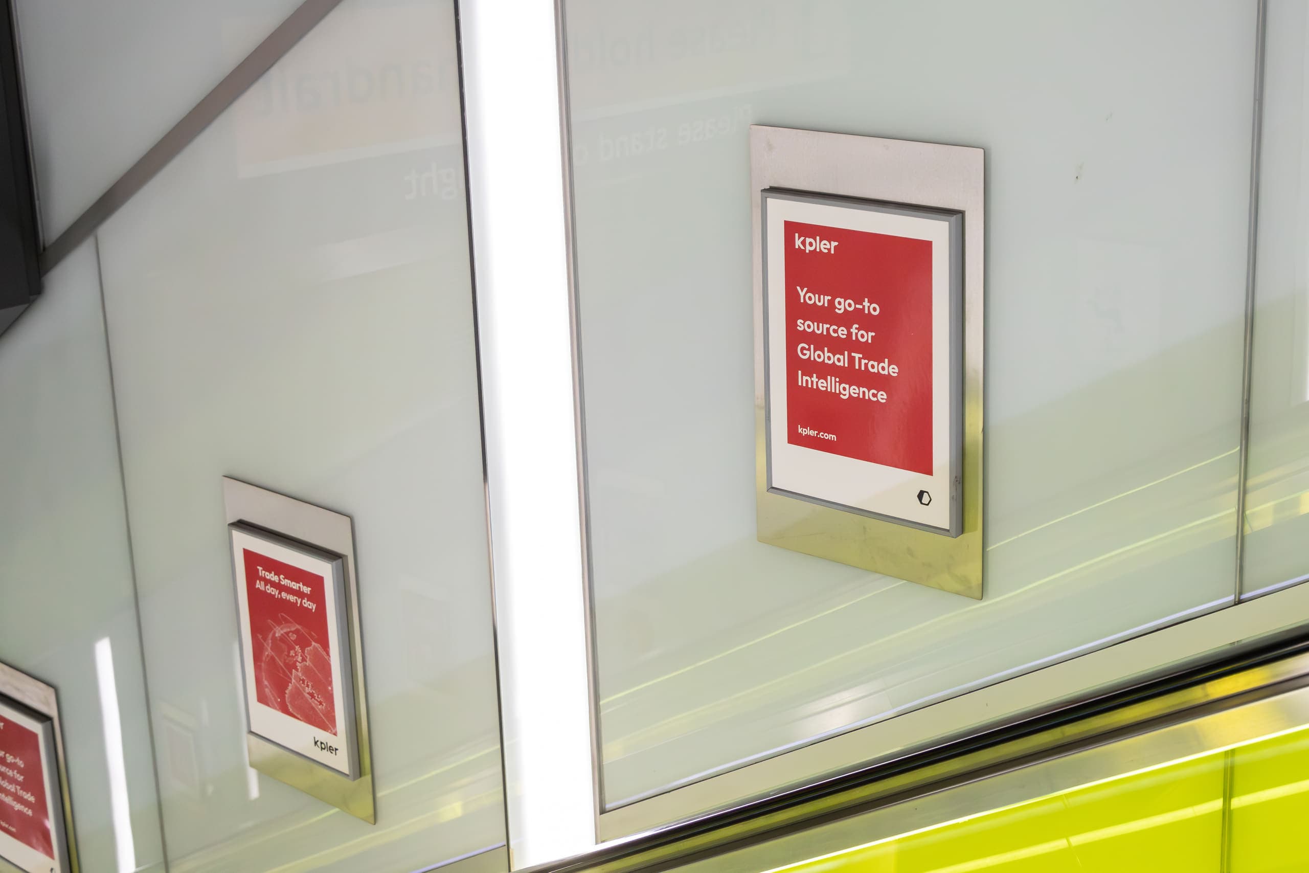 A close view of a static escalator panel advertising Kpler, with a second panel further down the shaft.