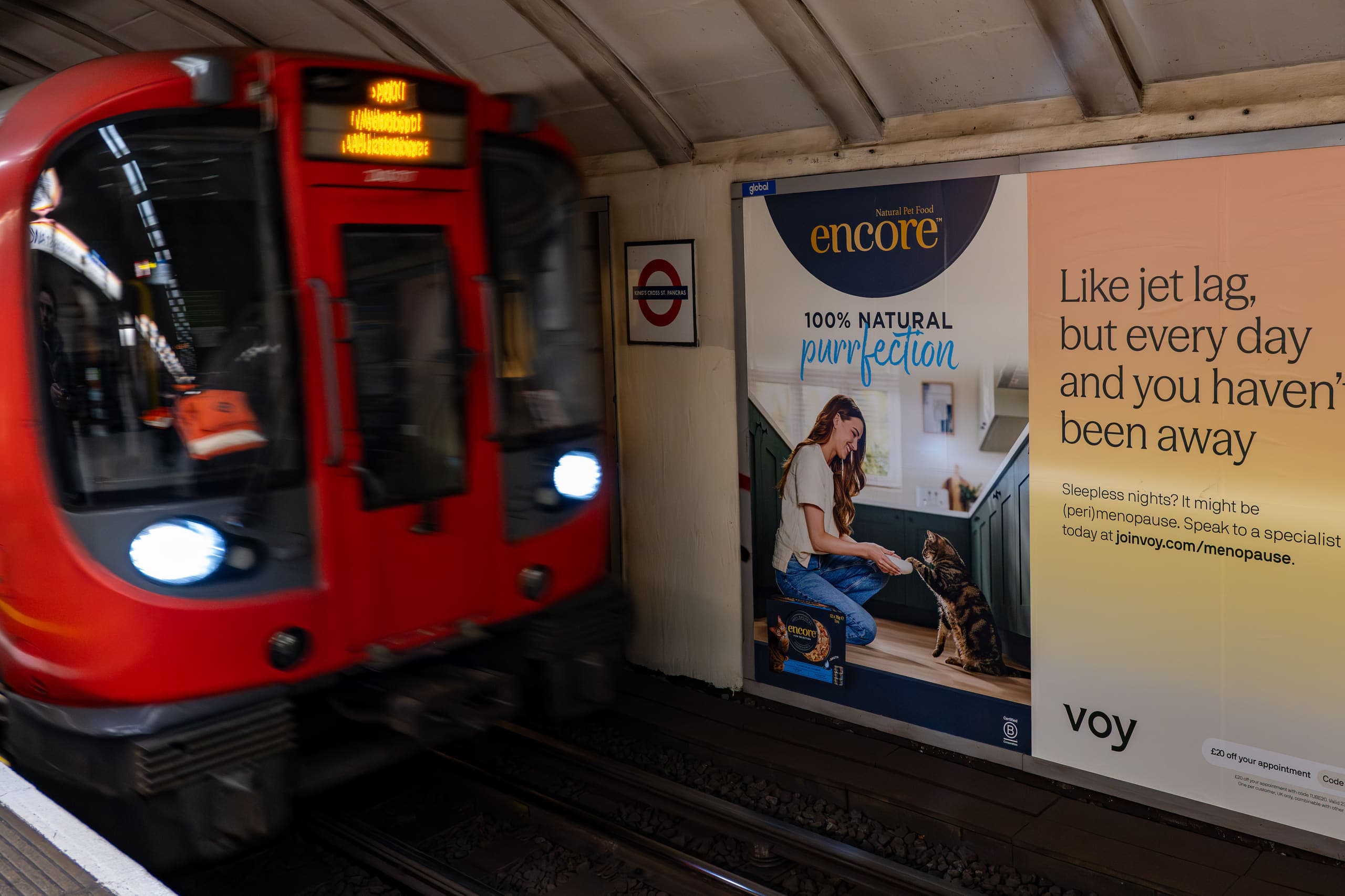 A cross-track poster advertising Encore on the platform wall at King's Cross St Pancras, with a train arriving.