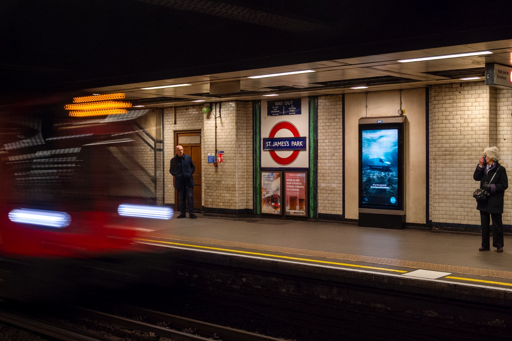A digital 6-sheet screen carrying a Xero advertisement on the platform at St James's Park, with a train passing and passengers waiting.