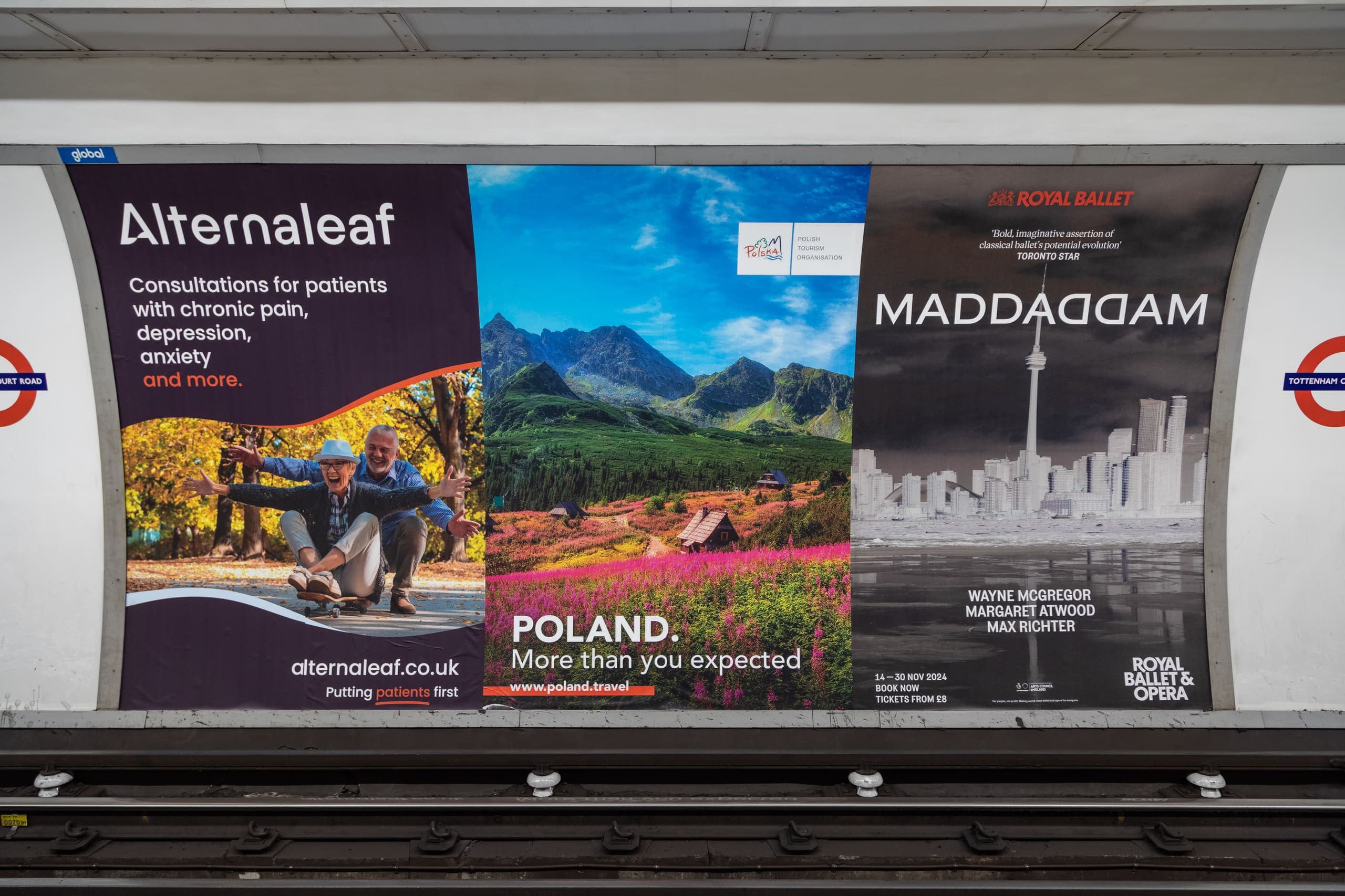 A run of three cross-track posters on the platform wall at Tottenham Court Road, the centre one carrying a Polish Tourism Organisation advertisement.