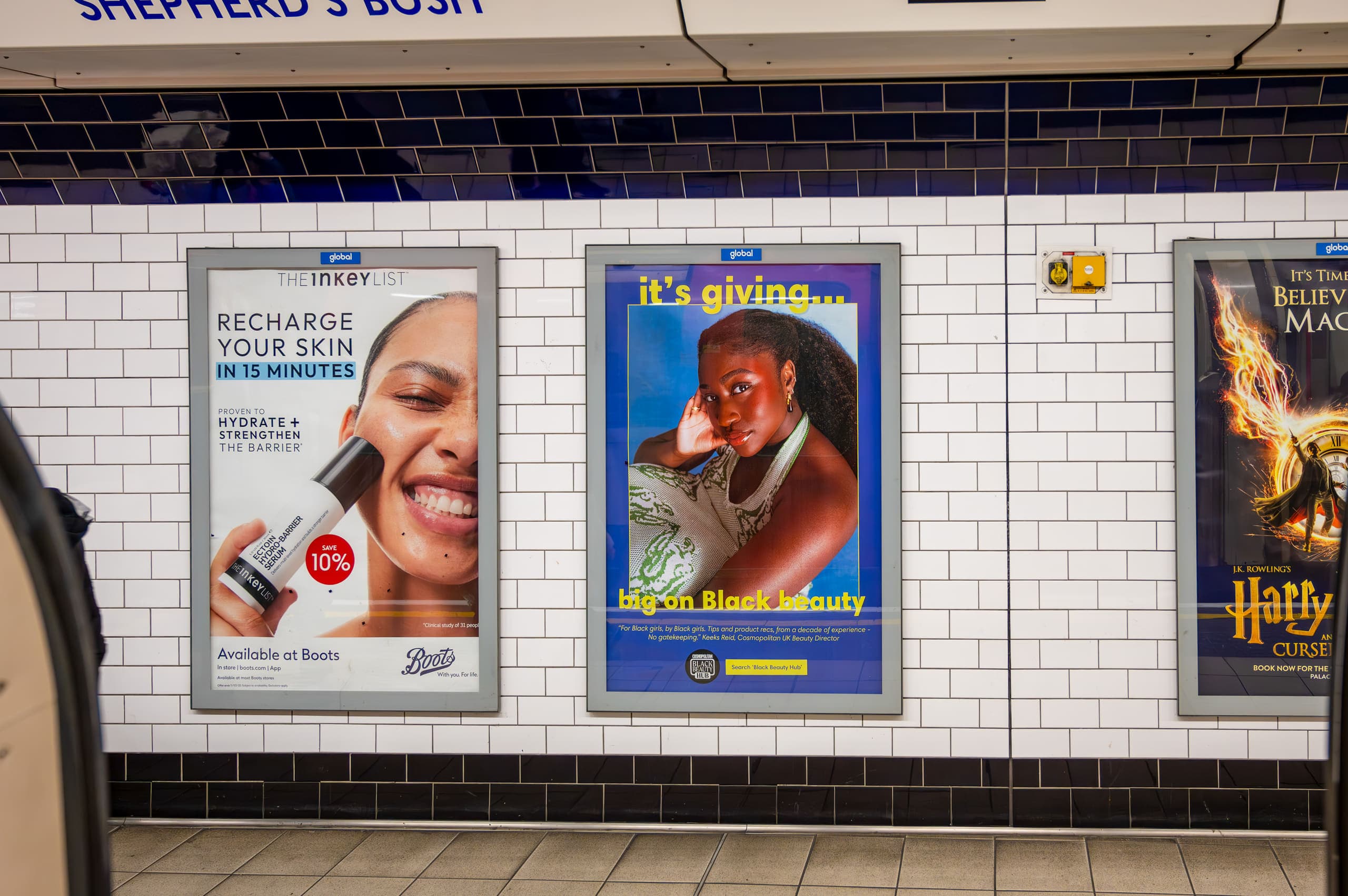 Framed poster sites on the tiled platform wall at Shepherd's Bush, the central one carrying a Cosmopolitan advertisement.