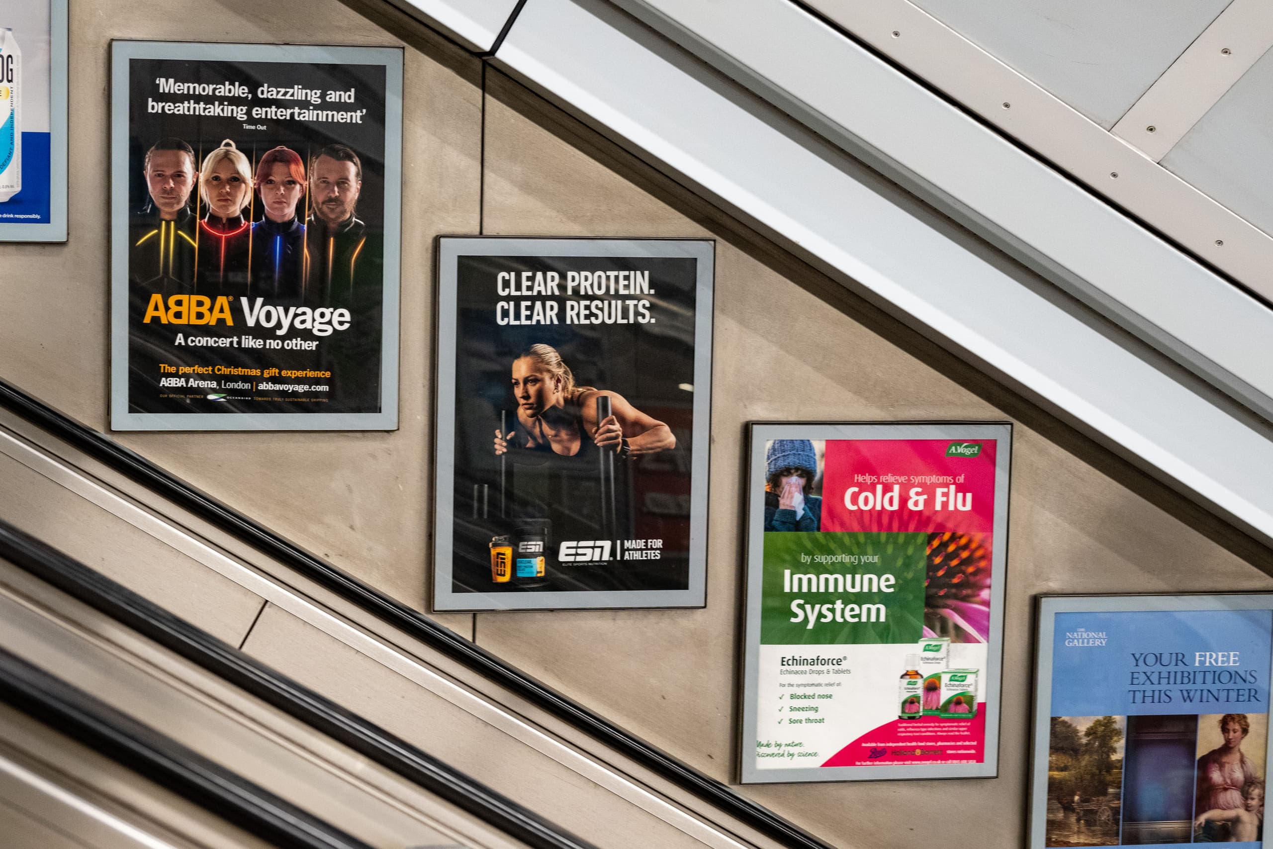 Static escalator panels beside an Underground escalator, one carrying an ESN advertisement.